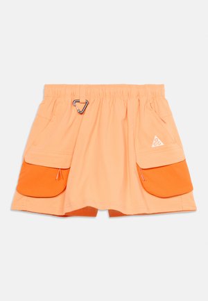 Light orange skirt with elastic waistband, two large front pockets with bright orange flaps, and a silver carabiner clip on the waist.