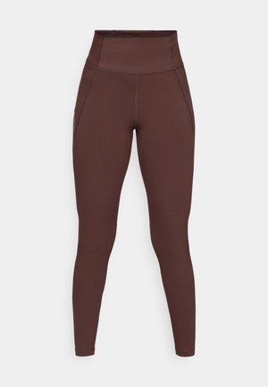 Høytlivede, mørkebrune hel lengde tights med synlige sømdetaljer og sidelommer mot en enkel bakgrunn.