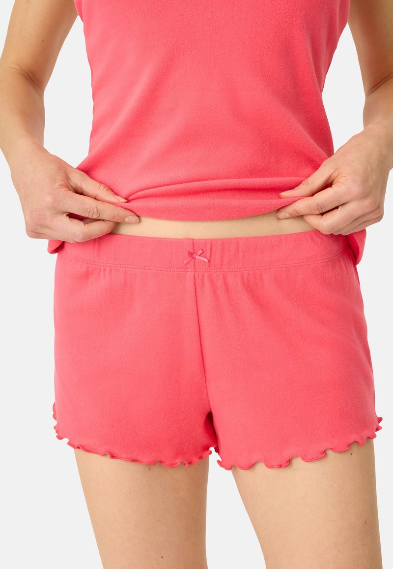 Roze shorts gemaakt van zachte stof hebben een gekartelde zoom en een klein strikdetail bij de taille. Combineer met een bijpassend roze mouwloos topje.
