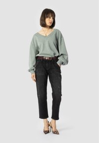 Jasnoszary, oversize sweter z dekoltem w serek połączony z czarnymi, postrzępionymi jeansami o prostym kroju oraz szpilkami w panterkę, podkreślony burgundowym paskiem.