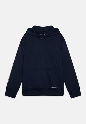 Tamno plavi dukserica izrađena od mekog materijala, ima veliki prednji džep i rebraste manžetne. Logo detalji na džepu i rukavu.