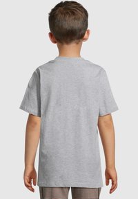 Gray short-sleeve t-shirt in soft fabric, featuring a crew neck and a relaxed fit. Worn with patterned pants, seen from the back.