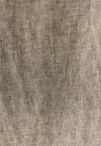 Samott szövet, tompa taupe színben, puha, texturált felülettel és diszkrét, egyenetlen szövési mintával. Simaság jellemzi, enyhe fényességgel.