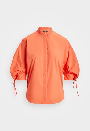 Lyseorange bluse med løse trekvartærmer samlet ved manchetter, høj krave med knaplukning og skjulte forknapper.