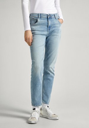Vaqueros de mezclilla azul claro con un ajuste relajado, diseño de cinco bolsillos y un ligero desgaste. Combinados con zapatillas blancas y calcetines.