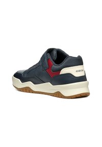 Zapatilla deportiva de cuero azul con acentos de malla, detalles rojos y una suela de goma blanca. Presenta un collar acolchado y una banda de rodadura texturizada para mayor agarre.