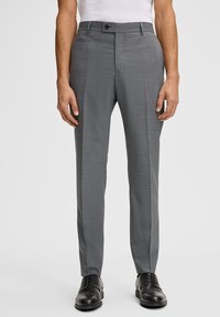 Grau maßgeschneiderte Hose aus strukturiertem Stoff, mit flacher Front, Seitentaschen und Knopfverschluss, kombiniert mit schwarzen eleganten Schuhen.