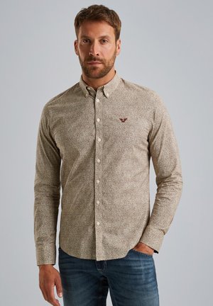 Bruin gemêleerd overhemd met lange mouwen, een button-down kraag en een klein geborduurd logo op de borst, gecombineerd met een blauwe jeans.
