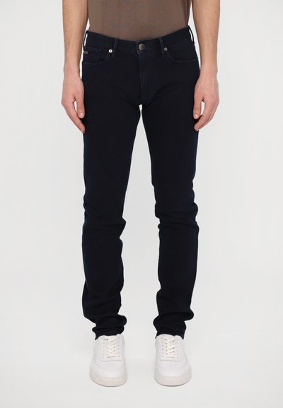 Tmavě modré skinny džíny vyrobené z denimu, s klasickým zapínáním na knoflík a zip, pěti kapsami a jemně vyšitým logem na zadní kapse.