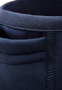Marineblauwe stoffen schoen met een gestructureerde bovenkant, voorzien van een gevoerde kraag en een contrasterende voering. Zichtbare stiksels op de zijkanten.