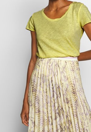 Limoengroen, t-shirt met korte mouwen en een ronde hals, gecombineerd met een geplooide rok met een gele en paarse slangprint.