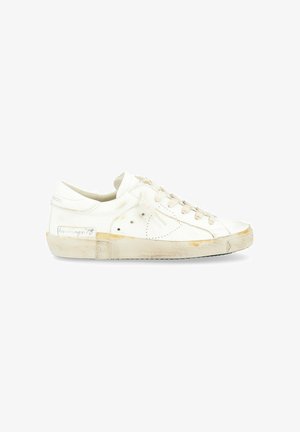 Sneaker in pelle bianca con profilo basso, punta arrotondata, design perforato, lacci color crema e suola in gomma leggermente usurata e ingiallita.