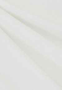 Tissu en coton blanc à texture lisse, drapé en plis doux, présentant son design uni sans motifs ni accents remarquables.