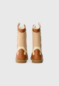 Tan and brown ankle boots feature a smooth leather upper, round toe, and decorative cutouts. Rubber sole, zip closure, and pull tabs.