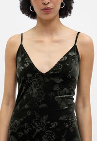 Čierne sametové šaty s hlbokým V-výstrihom a tenkými ramienkami, ktoré majú jemný vzor ruží a hladkú textúru.