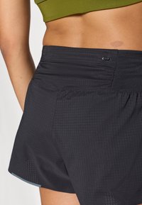 Μαύρα αθλητικά σορτς με υφή, που διαθέτουν ελα στική μέση και μια μικρή τσέπη στη πίσω πλευρά.