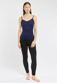 Navy tank top with lace trim and adjustable straps, paired with black leggings. Both garments are fitted and made of stretchy material.