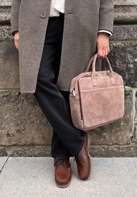 Cappotto grigio in lana, pantaloni neri, scarpe in pelle marrone e una borsa in suede rosa chiaro con doppi manici e una tasca frontale.
