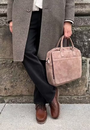 Cappotto grigio in lana, pantaloni neri, scarpe in pelle marrone e una borsa in suede rosa chiaro con doppi manici e una tasca frontale.