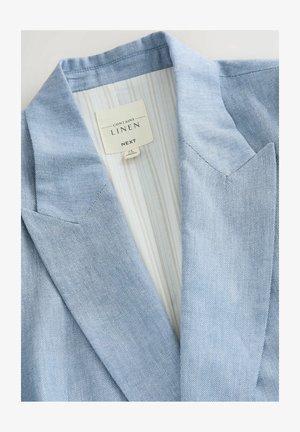 Blazer en lin bleu clair avec un revers à niches et une doublure intérieure rayée. L'étiquette indique "Contient du lin" avec le nom de la marque "NEXT."
