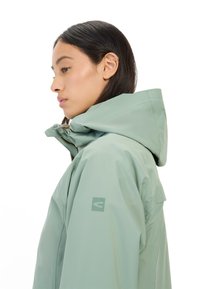 Lichtgroene waterdichte jas met een capuchon, voorzien van een rits, een verstelbare hals en een logo op de linker mouw. Glad textiel.