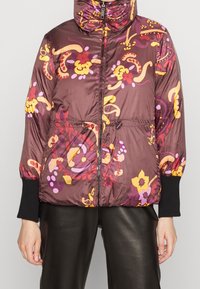 Doudoune couleur bordeaux foncé avec des motifs floraux en jaune, rose et violet. Elle est dotée de poignets élastiques et d'une taille à cordon de serrage.