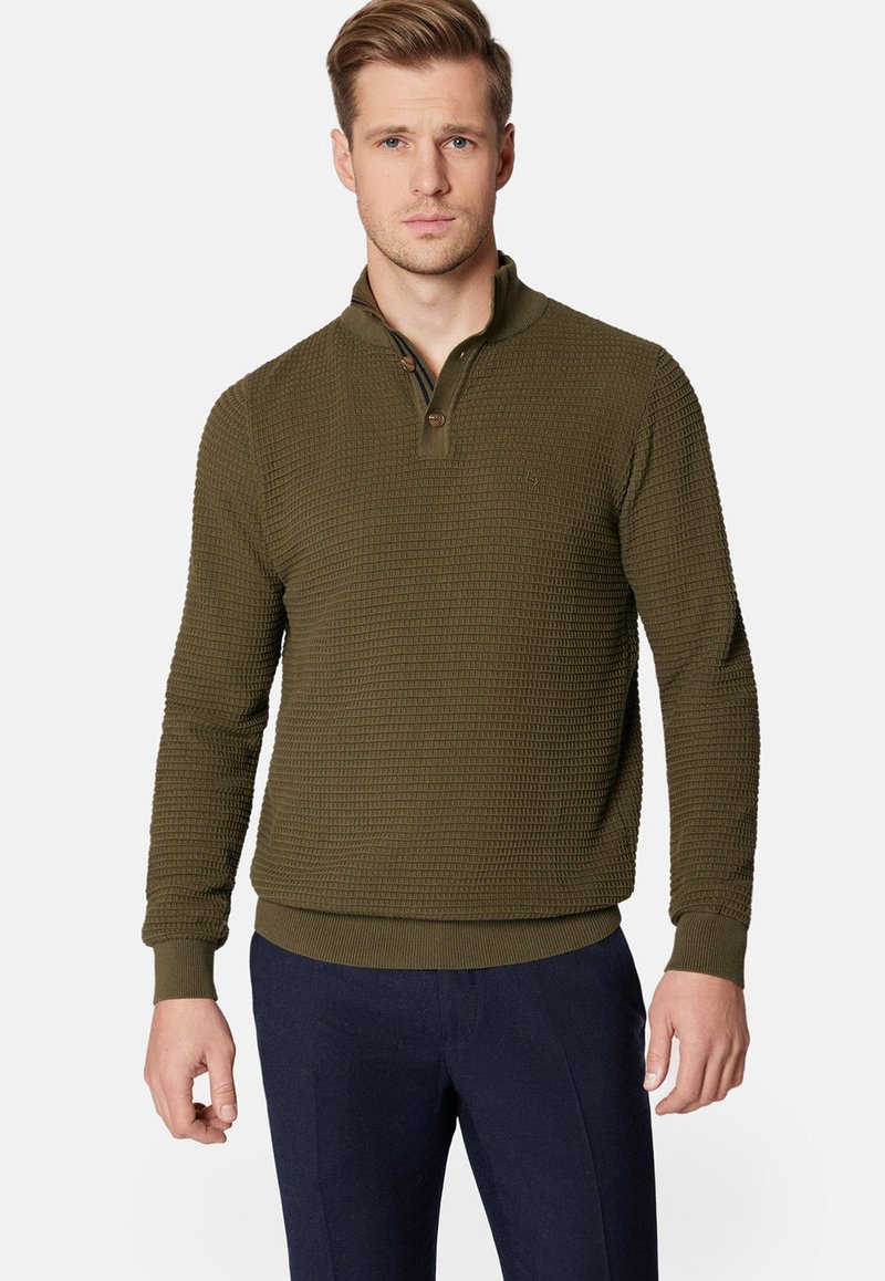 Oliwkowy pulower o fakturowanym, wafelowym splocie, z półguzikowym zapięciem oraz ściągaczami przy mankietach i dolnym obszyciu. Minimalne logo na przodzie.