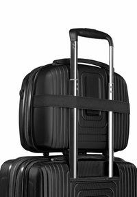 Ensemble de valises rigides noires avec une finition texturée, comprenant une poignée télescopique et une sangle rembourrée pour maintenir la plus petite valise sur le dessus.