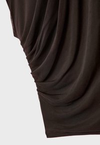 Lähikuva tummanruskeasta kankaasta, jossa on kerättyjä laskoksia ja hieno verkkokuvio vaalealla taustalla.