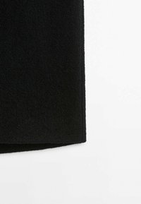 Tissu noir texturé avec un bord d'ourlet droit, présenté sur un fond blanc.