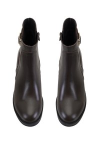 Bottines en cuir brun avec une finition lisse, fermeture éclair sur le côté et une sangle décorative avec une boucle métallique. Semelle plate, bout rond.