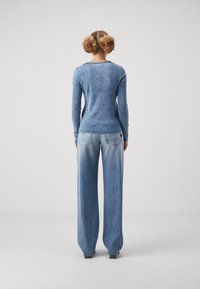 Blå tröja med långa ärmar och mjuk textur, kombinerad med ljusblå jeans med vida ben, som har en blekt tvätt och en avslappnad passform.