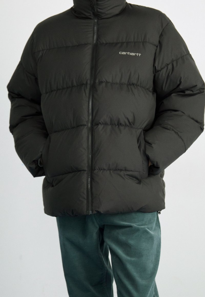 Sort oppustelig jakke med vandrette quiltede sektioner, høj krave og lynlåslukning. Bemærkelsesværdigt mærke logo på venstre bryst.