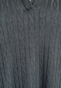 Tamno sivi pleteni pulover s teksturiranim uzorkom pletenice i dizajnom s V-izrezom. Tkanina izgleda mekano s ugodnim završetkom.