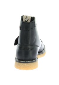 Botas de tobillo de cuero negro con un acabado suave, que cuentan con una puntera redondeada, acentos cosidos y una suela de goma marrón. Con tira de arrastre en la parte posterior.