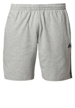Man walking wearing a navy Adidas t-shirt, light grey shorts with black stripes, black socks, and black Adidas sneakers.