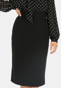 Czarna spódnica ołówkowa o średniej długości. Posiada szeroki pasek w talii oraz przednie kieszenie szwowe. Gładki materiał bez widocznych wzorów.