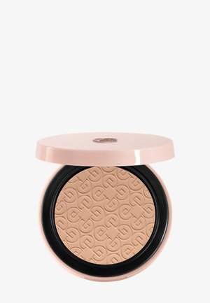 Poudre compacte beige avec motif géométrique en relief dans un étui rond en plastique rose et noir avec couvercle partiellement ouvert.