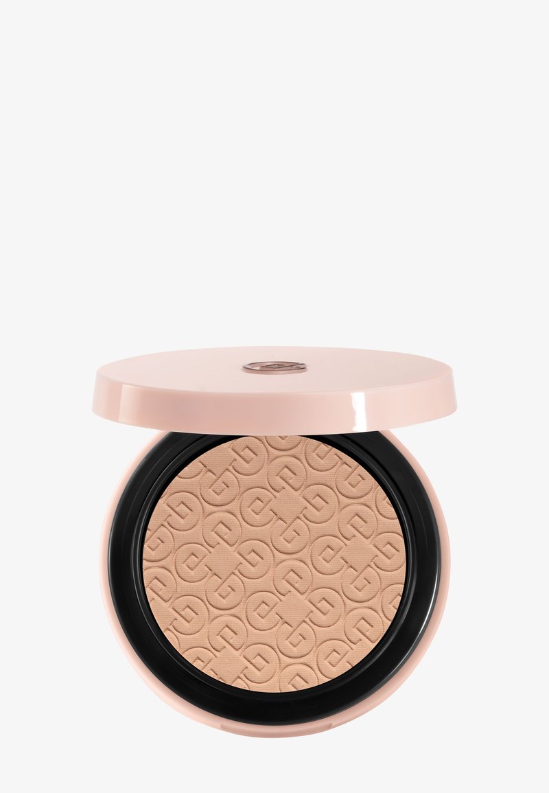 Poudre compacte beige avec motif géométrique en relief dans un étui rond en plastique rose et noir avec couvercle partiellement ouvert.