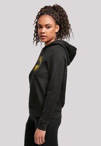 Black hoodie featuring a front pocket, drawstring hood, and gold graphic design on the chest. Soft fabric with a relaxed fit.