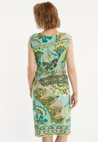 Robe sans manches dans un mélange de vert, bleu et beige. Présente un motif floral, une taille cintrée et une texture lisse, avec une coupe à mi-longueur.