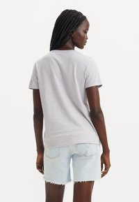 Light gray striped t-shirt with short sleeves, relaxed fit, and round neckline, paired with light blue distressed denim shorts.