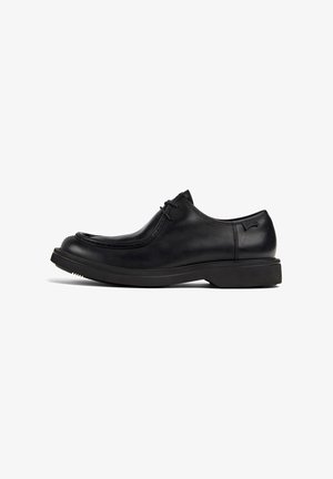 Schwarze Leder-Schnürschuhe mit dicker Sohle und runder Zehenpartie, von der Seite auf einem weißen Hintergrund betrachtet.