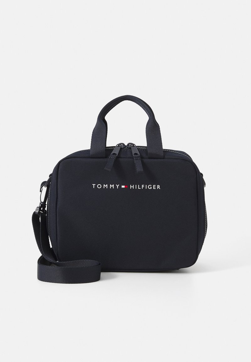 Sac rectangulaire navy avec texture en tissu, fermeture à double zip, poignées supérieures et bandoulière réglable. Avec logo sur le devant.