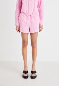 Rosa stripete skjorte med knapper kombinert med matchende shorts med snøring i livet. Brukt sammen med svarte, plattform sandaler.