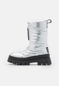 Srebrny syntetyczny botek na kostkę z połyskującym wykończeniem, grubą czarną gumową podeszwą, zapięciem na zamek i teksturowanym wzorem na materiale.