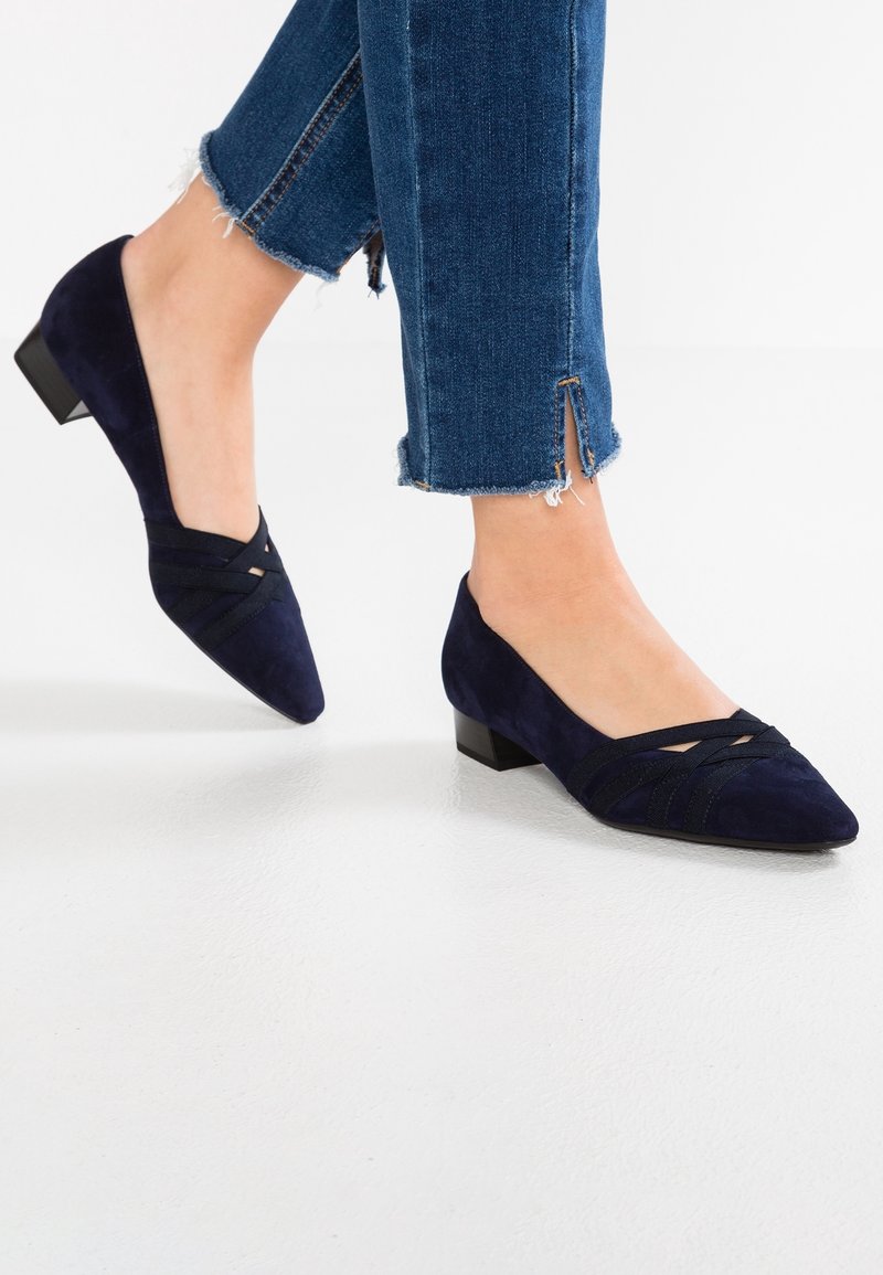 Ballerines en daim bleu marine à bout pointu, dotées de brides croisées à l'avant et d'un petit talon carré. Portées avec un jean à ourlet effiloché.