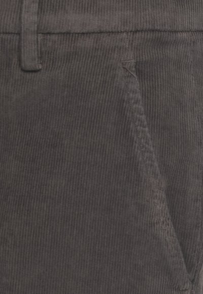 Primo piano di una tasca di pantaloni in velluto a coste grigio scuro con cuciture visibili e passante per cintura.