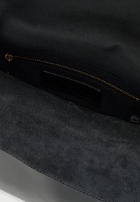 Sort håndtaskeindvendig med blød ruskindsstruktur, lynlåslomme med gylden lynlås og stofbeklædning for ekstra organisering.