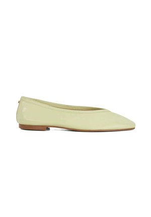 Chaussure de ballet plate brillante de couleur jaune pâle avec bout pointu et petit talon marron, vue de côté sur fond blanc.